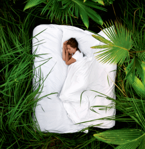 Woman-asleep-on-mattress-on-grass.png