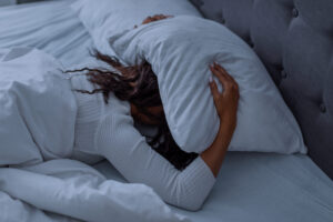 stressed-black-woman-covering-head-under-pillow-ly-2023-11-27-05-12-12-utc-scaled.jpg