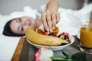 cropped_image_beautiful_brunette_girl_morning_croissant_orange_juice_banana_pomegranate_tray_rose_1.webp