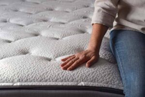 woman-sitting-on-a-brand-new-mattress-and-touching-2023-10-23-19-31-27-utc.jpg